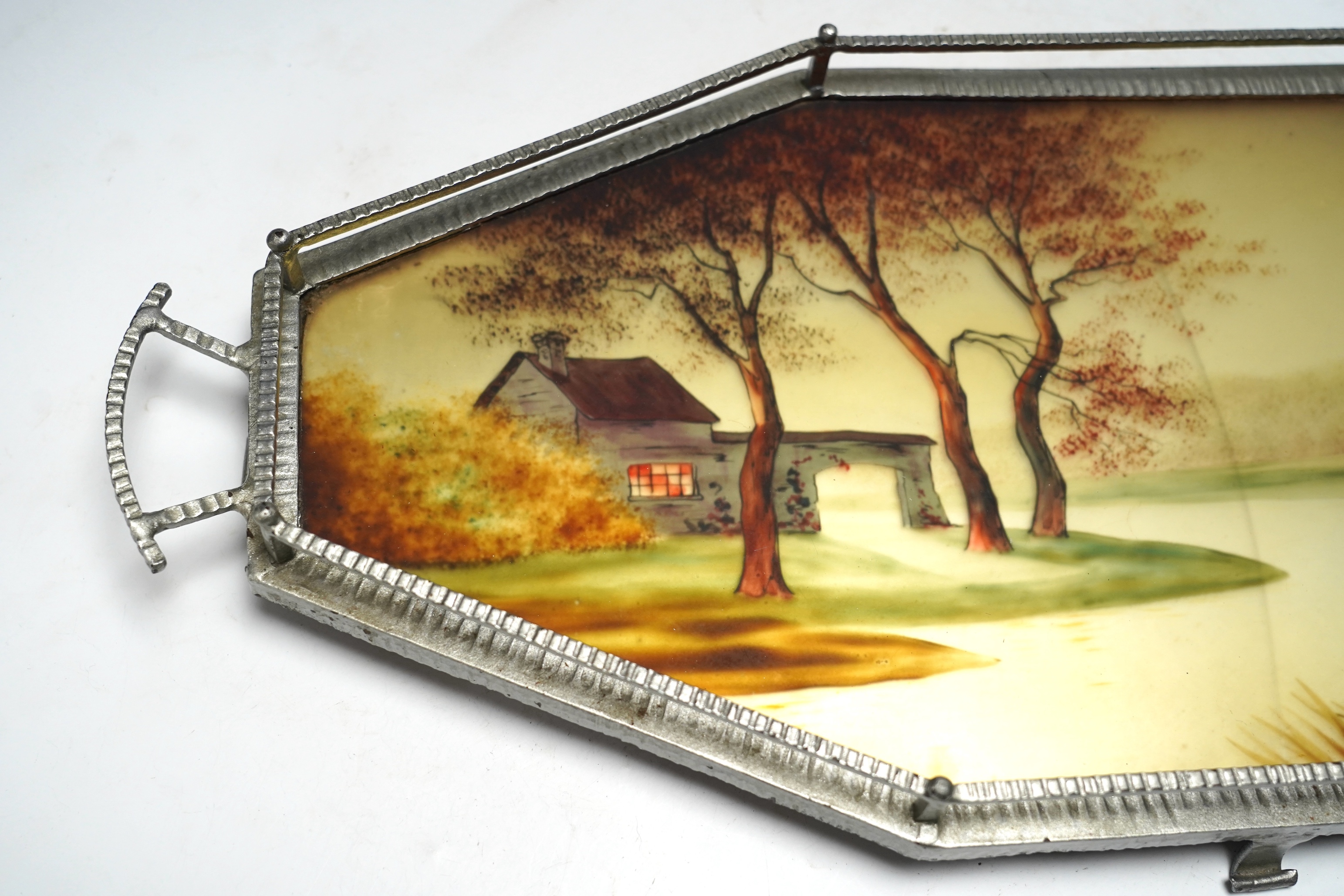 An Art Deco reverse painted and wrought iron tray, with a gallery, centred with a reverse painted landscape scene, signed 'Germonde', 70cm, damaged